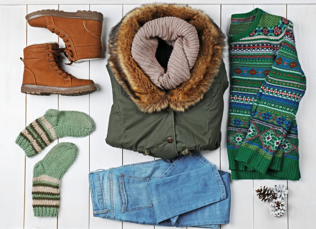 flatlay for winter family photo shoot green themed clothing jeans sweater jacket socks boots