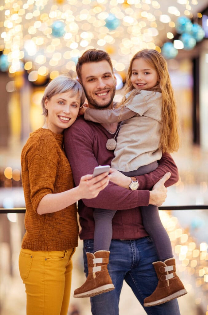 Family enjoying holiday lights at a festive event, capturing joyful moments together.