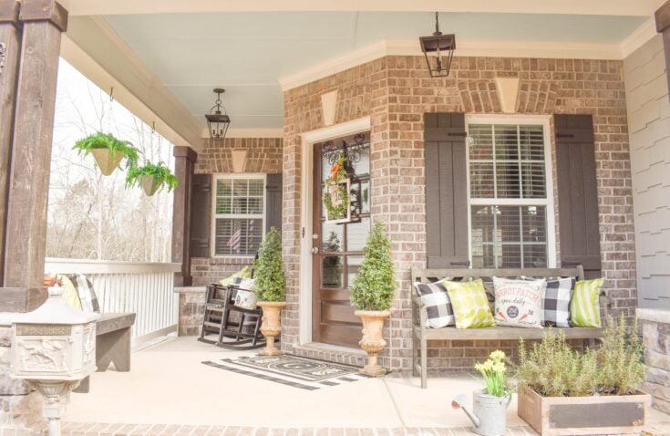 Cozy brick front porch with seating, potted plants, and decorative accents, perfect for outdoor relaxation and charming curb appeal.