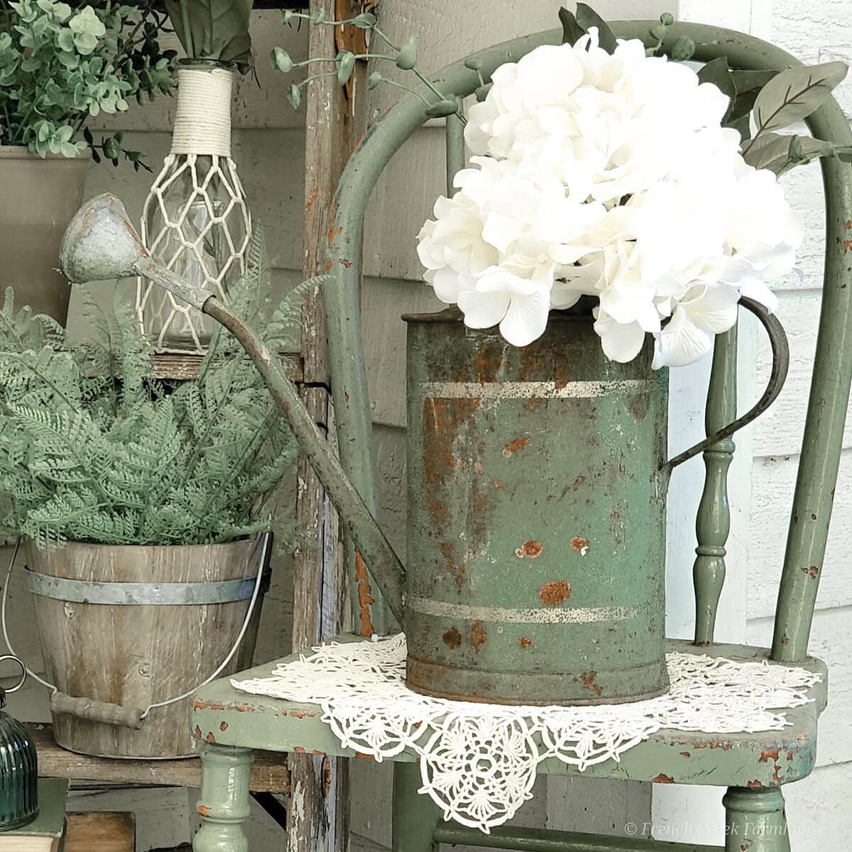 Rusty green vintage watering can with white hydrangea flowers, rustic garden decor, shabby chic vintage style, floral arrangement, outdoor garden aesthetic.