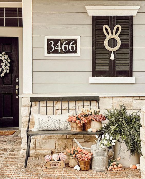 Beautiful spring front porch with floral arrangements, rustic decor, and festive Easter eggs creating a welcoming and cozy outdoor space.