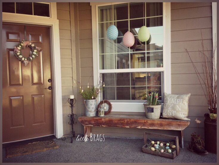 Colorful Easter paper lanterns hanging in front of a house window, decorated with spring-themed items like a floral wreath, potted tulips, and Easter eggs for festive holiday decor.