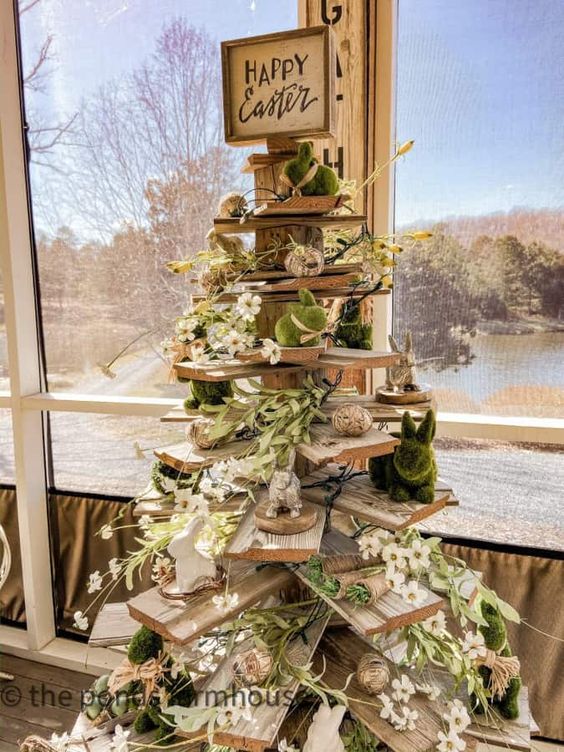 Whimsical Easter decor featuring a rustic wooden tree adorned with bunny figurines, white flowers, and “Happy Easter” sign, perfect for spring celebrations and festive home accents.