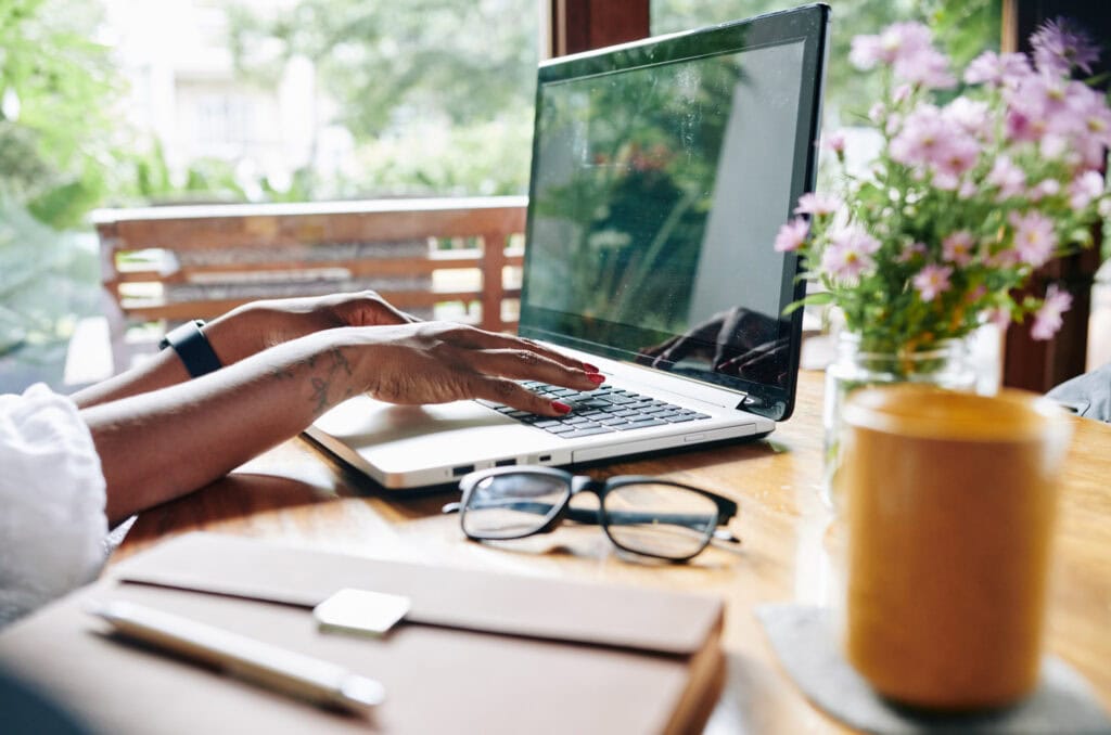 Light-filled home office with laptop, glasses, and potted flowers, ideal for creative work and relaxation at A Hundred Affections.