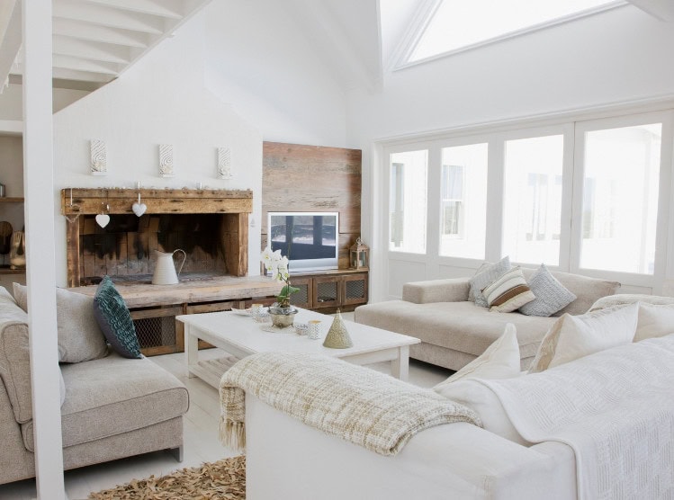Cozy living room with white walls and natural light, featuring comfortable sofas, a rustic fireplace, and modern decor, ideal for relaxing and entertaining.