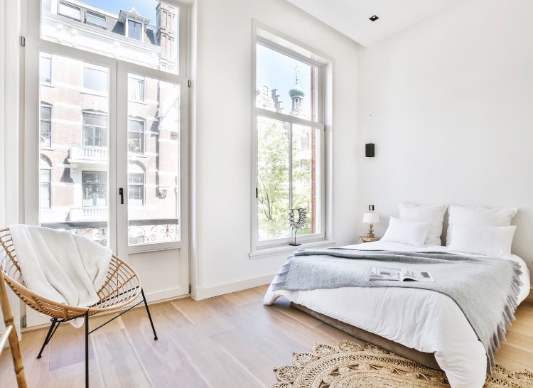 Bright, airy bedroom with large windows, minimalist decor, and natural light, perfect for a cozy, relaxing retreat in an elegant urban apartment.