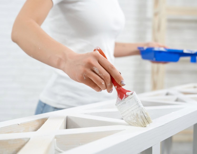 Colorful DIY furniture painting using white paint and a brush for home decor makeover.