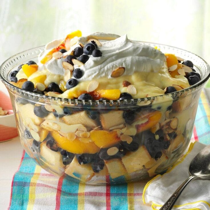 Fresh fruit trifle dessert layered with blueberries, peaches, whipped cream, and toasted almonds, perfect for summer gatherings and special occasions.