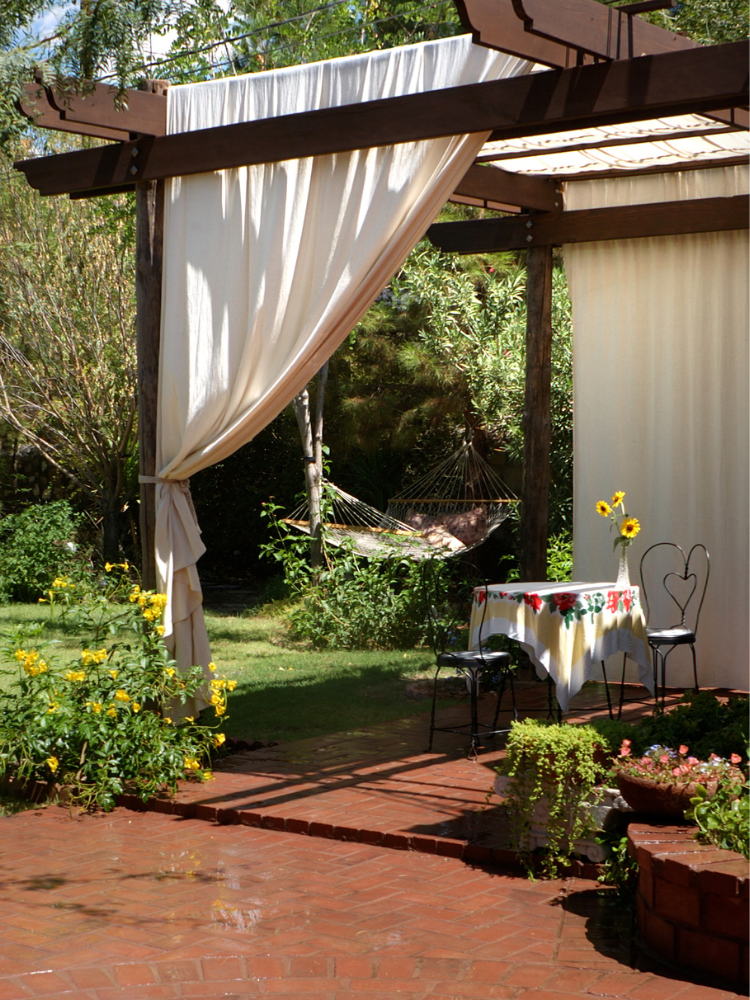 patio pergola with draped curtains and bistro table and chair