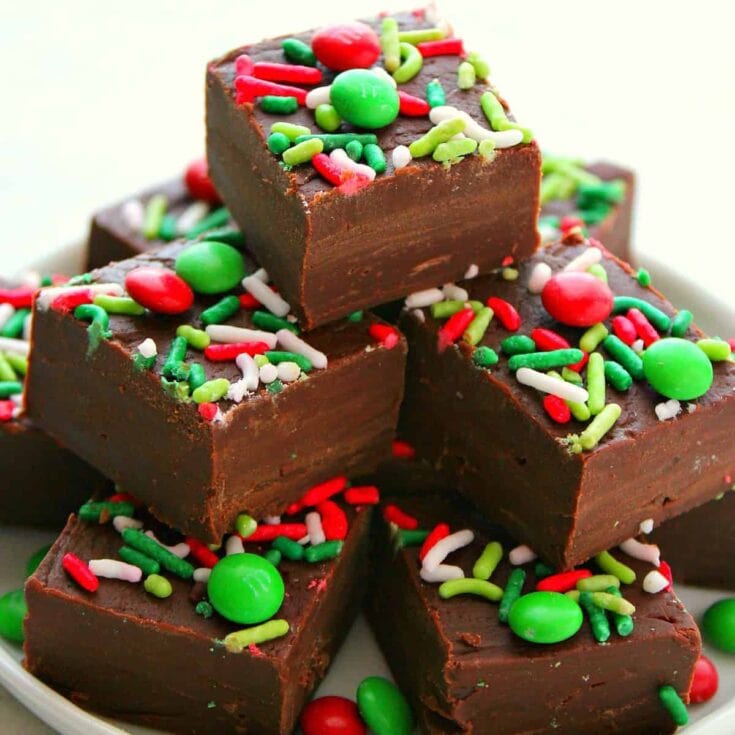 Chocolate fudge brownies topped with colorful red, green, and white sprinkles and candies, perfect for holiday celebrations and desserts.