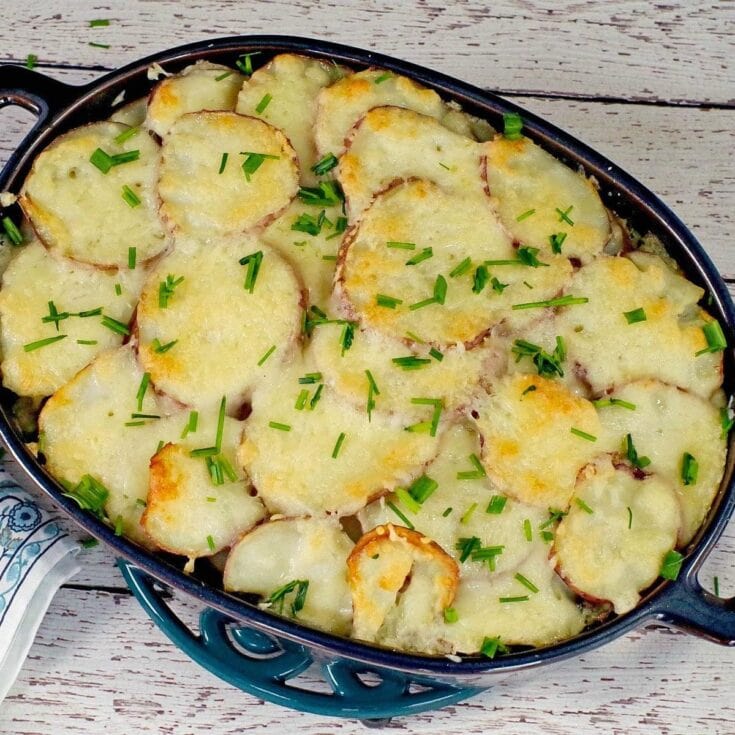 Golden cheesy scalloped potatoes baked with fresh chives in a skillet, perfect for comfort food and family dinners.