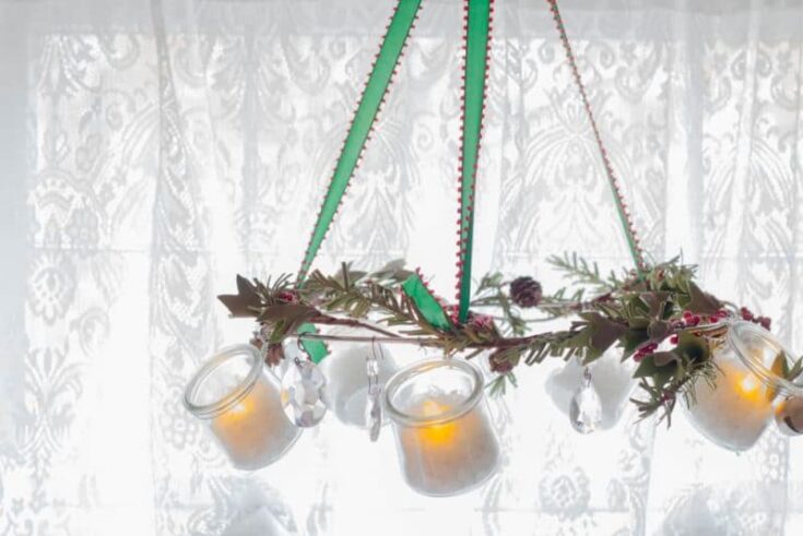 Hanging advent candle chandelier with festive greenery and crystal accents, perfect for holiday decor.