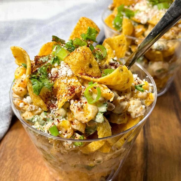 Creamy chicken salad with tortilla chips, chopped green onions, crumbled cheese, and spices served in clear glasses, perfect for a flavorful, comforting meal or appetizer.