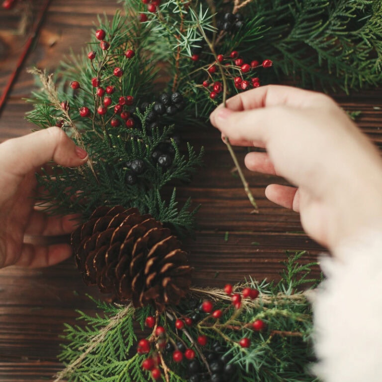 Green holiday wreath with pinecones, red berries, and evergreen foliage for Christmas decor close-up.