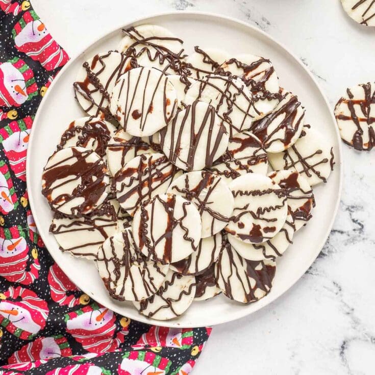 Buttercream peppermint cookies drizzled with chocolate on a white plate, festive Christmas dessert, holiday treats for Christmas gatherings, peppermint-flavored cookies with chocolate decoration, seasonal holiday baking for the winter holidays.