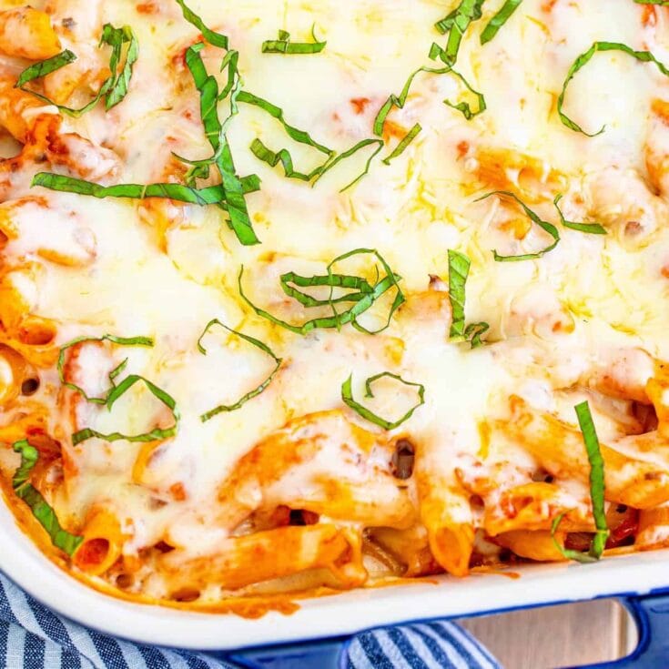 Creamy baked pasta with melted cheese and fresh basil garnish, served in a white casserole dish. Perfect comfort food for family dinners or casual gatherings.