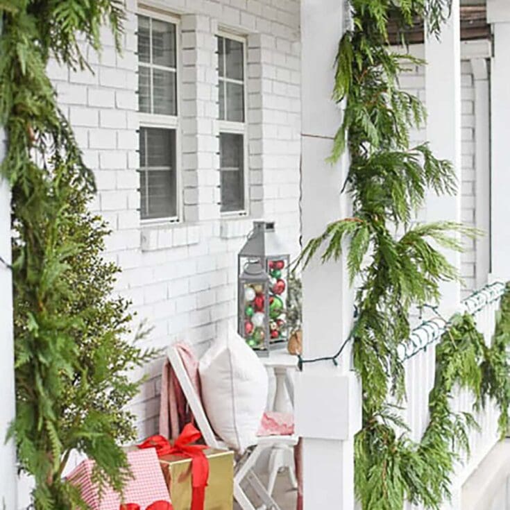 Ornamental holiday porch decorated with green garland and wrapped gifts for Christmas.