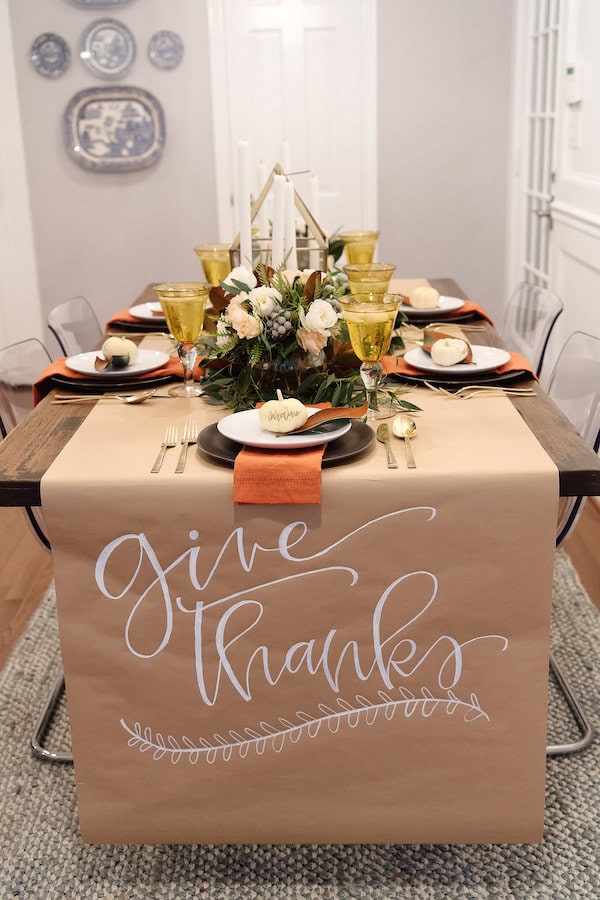 Elegant thanksgiving table setup with a "give thanks" sign, floral centerpiece, gold and white accents, perfect for autumn or harvest celebration, family gathering or gratitude event.