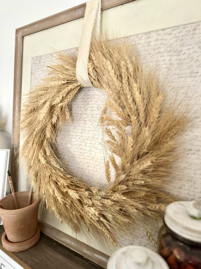 Crisp dried wheat stalks arranged in a circular wreath decor with a neutral, natural aesthetic, perfect for rustic or farmhouse-themed home interior decor.