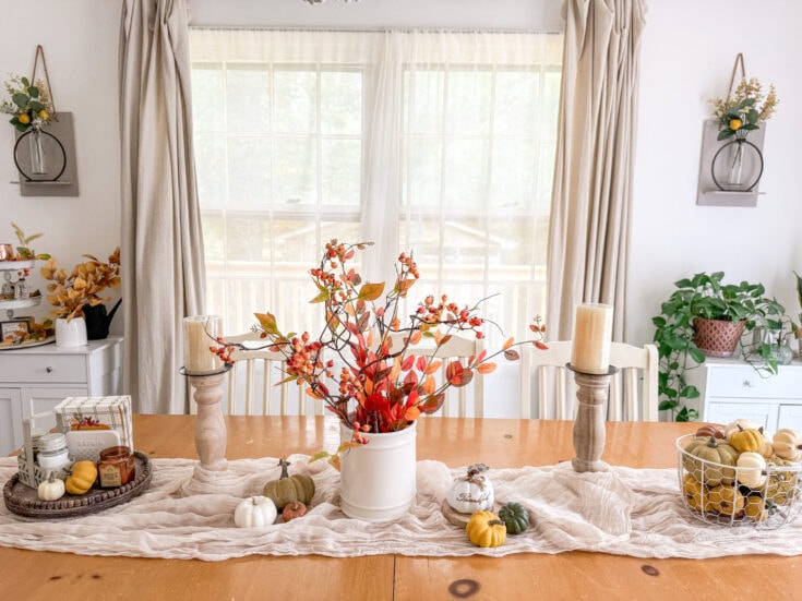 Vase with autumn foliage and pumpkins centerpiece on dining table, cozy home decor, fall holiday table setting, warm and inviting ambiance, seasonal Thanksgiving decorations.