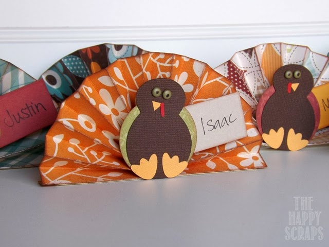 Colorful paper place cards with turkey embellishments and handwritten names, perfect for Thanksgiving or fall table settings.