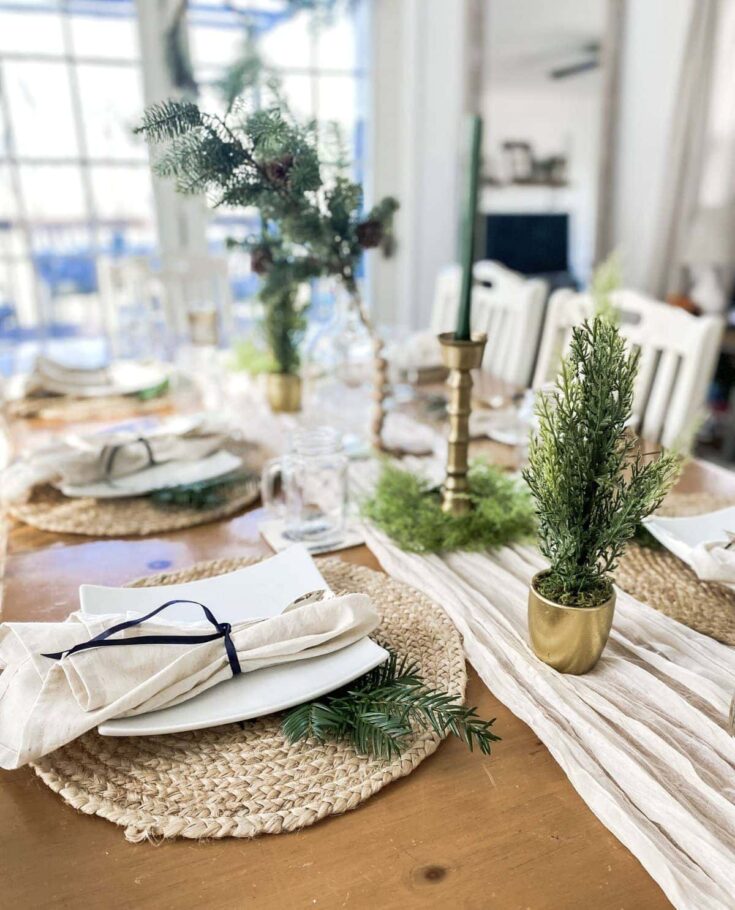 Elegant holiday table setting featuring greenery, candles, and natural accents for Christmas or winter celebrations.