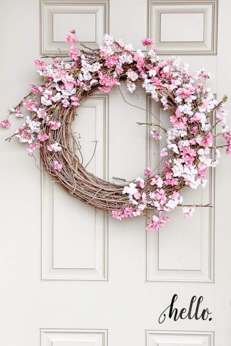 Pink and white flower wreath hanging on a white door, perfect for spring or Easter decor, by A Hundred Affections.