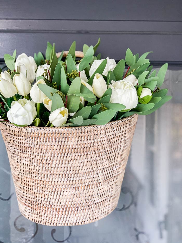 White tulips and greenery in a woven basket for elegant floral arrangements - A Hundred Affections.