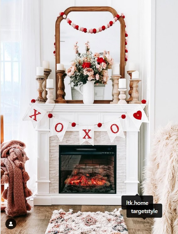 Cozy Valentine's Day fireplace decorated with floral arrangement, "XOXO" banner, and festive garland, creating a warm and romantic home decor setting.
