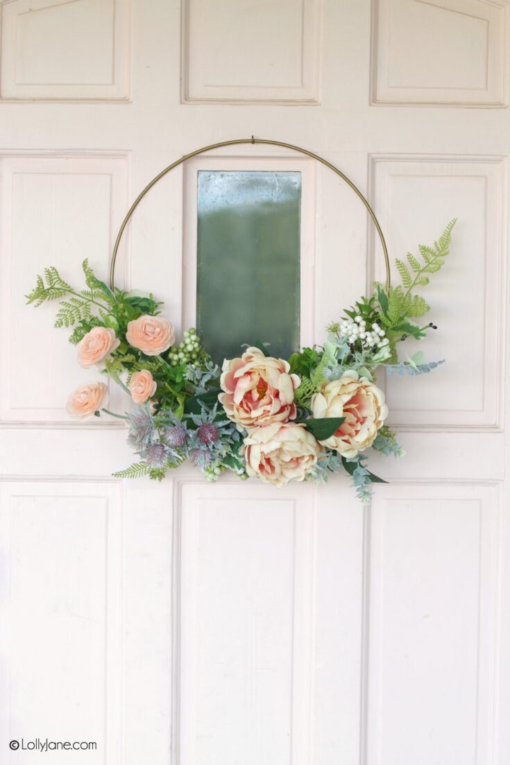 Soft pink and cream floral wreath with greenery hanging on a white door, perfect for home decor or special occasions.