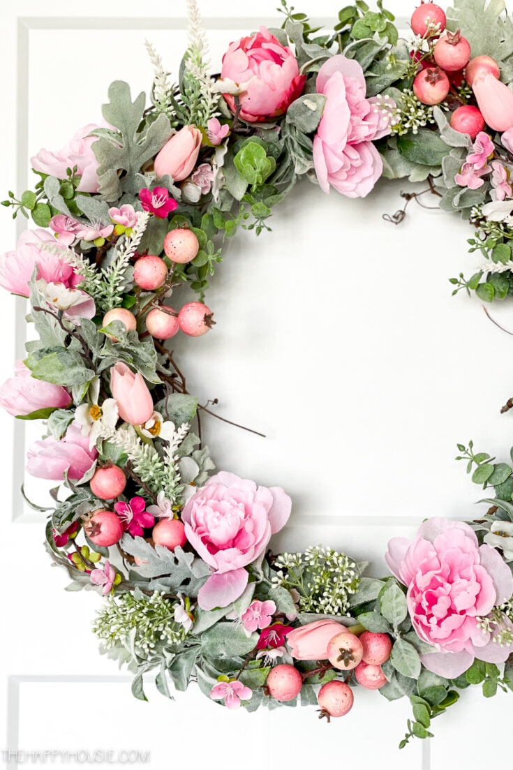 Pink floral wreath with peonies, roses, and berries for spring home decor and wedding centerpieces. Beautiful seasonal floral arrangement showcasing fresh flowers and greenery.