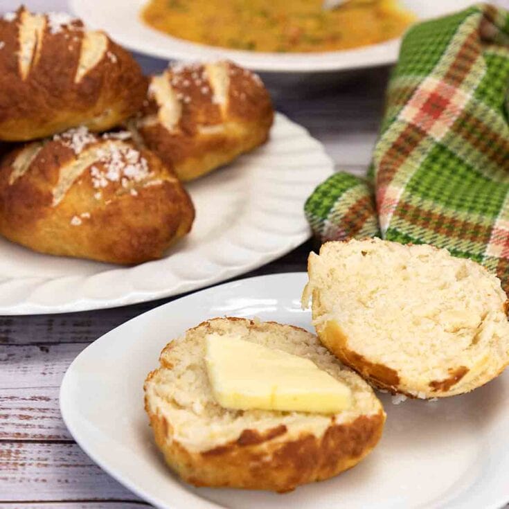 Buttery homemade dinner rolls with salted butter on a white plate, fresh baked bread with coarse salt, cozy kitchen setting, bread baking, comfort food, homemade baked goods, holiday bread, soft and warm bread, rustic bread, freshly baked bread, comforting bakery treats.