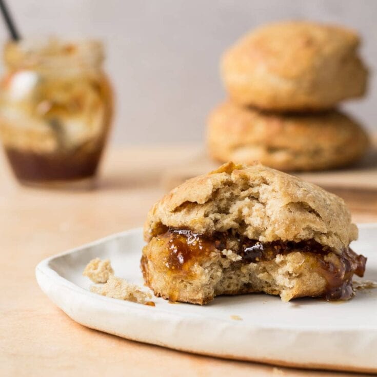 Butter symbol cookie with caramel filling on a white plate, stacked cookies and a jar of caramel sauce in the background, delicious homemade sweet treat, perfect for dessert or snack, bakery-style cookies, soft and chewy texture, golden-brown crust, indulgent caramel center, cozy comfort food, A Hundred Affections, bakery and dessert inspiration.