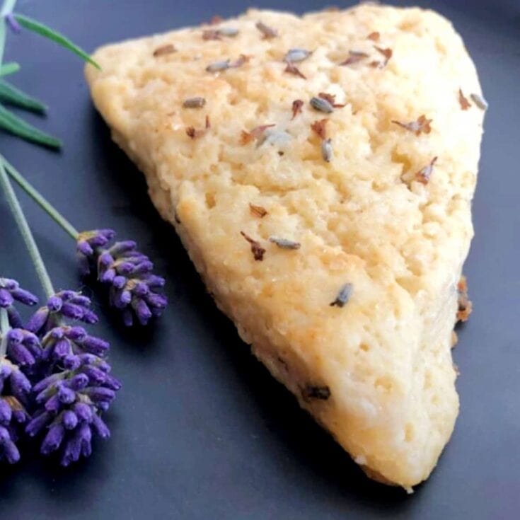 Buttermilk breaded chicken breast topped with herbs, served on black plate with lavender sprigs for garnish, highlighting delicious comfort food and elegant presentation.