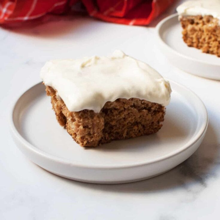 Soft, moist carrot cake slice topped with smooth cream cheese frosting on a white plate, perfect for dessert or celebration. Delicious homemade carrot cake recipe from A Hundred Affections.