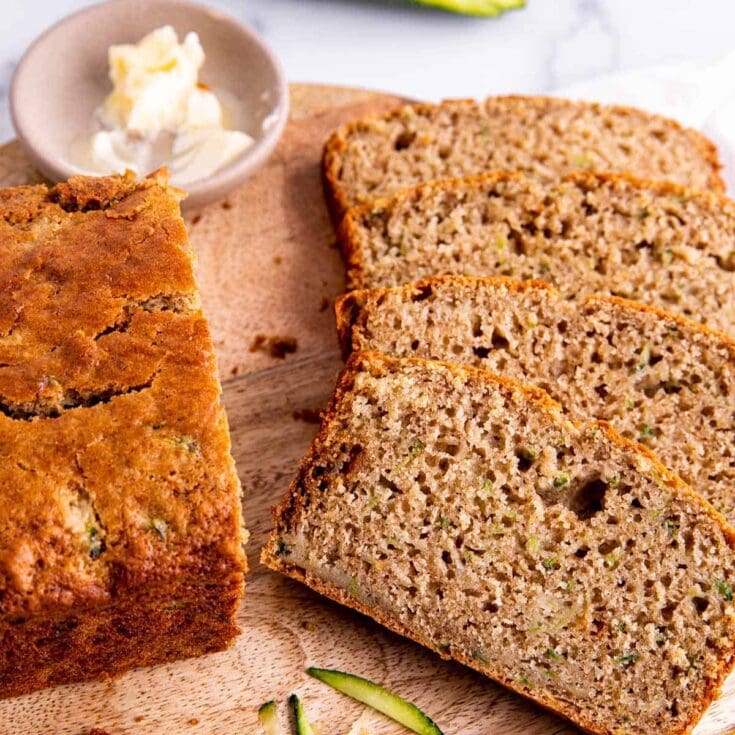 Homemade banana bread with slices on a wooden board, served with a side of butter, perfect for breakfast or snack. Moist, flavorful banana loaf made with ripe bananas and natural ingredients.