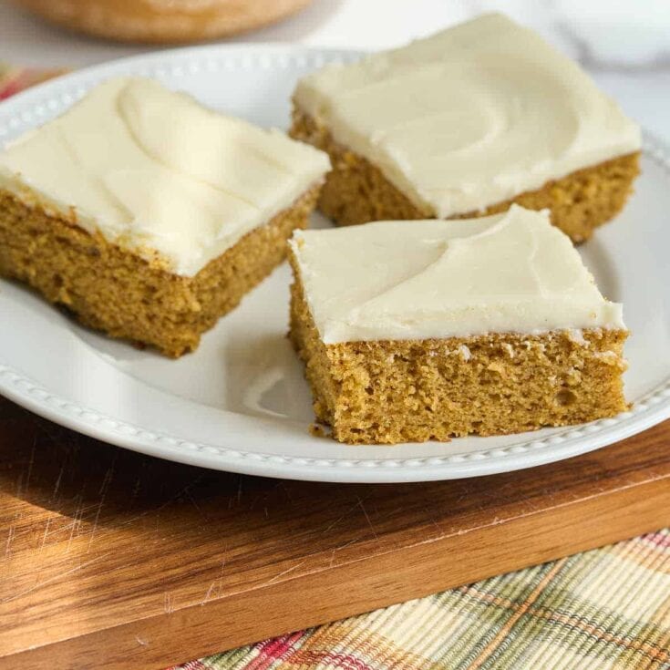 Slice of homemade carrot cake with cream cheese frosting on a white plate.