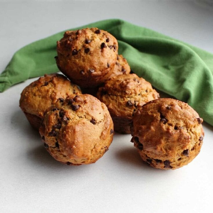 Golden chocolate chip cookies on a white surface with a green cloth, showcasing homemade bakery treats perfect for comfort food, dessert, and snacking.