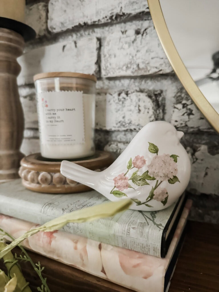 vintage ceramic bird with floral print on vintage books with candle on mantel