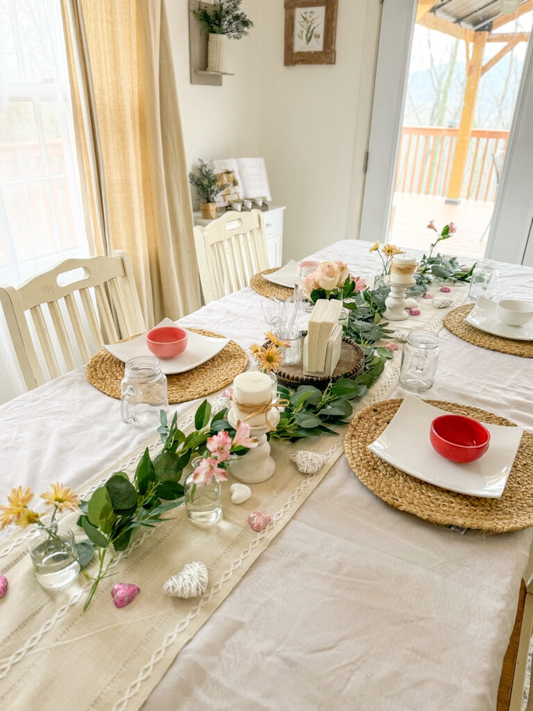 Valentine's tablescape with eucalyptus garland, bud vases, and heart bowls