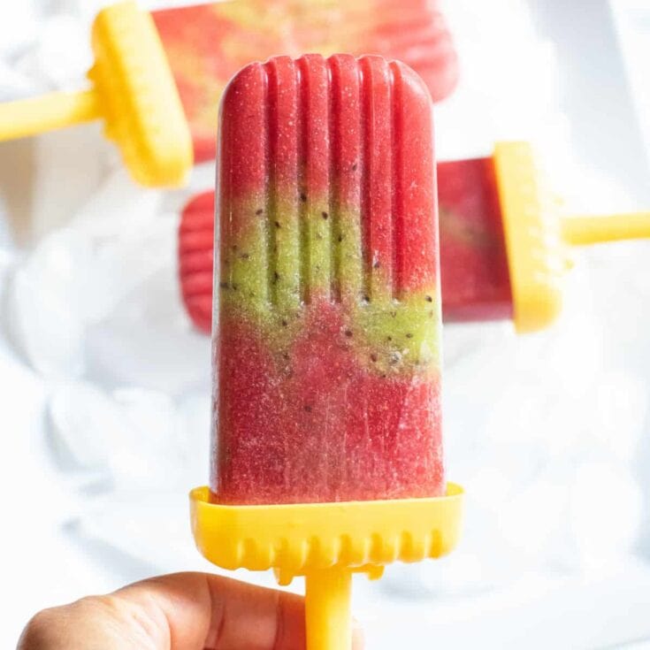 Refreshing watermelon and mango popsicle with vibrant red, green, and yellow colors, perfect for summer treats and homemade dessert recipes from A Hundred Affections.
