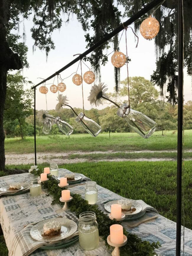 country summer tablescape with quilt and table bar, hanging vases