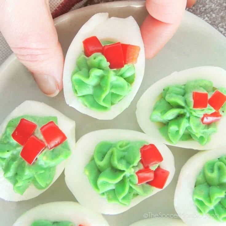 Colorful deviled eggs with green filling and red toppings, perfect for party appetizers or holiday snacks.