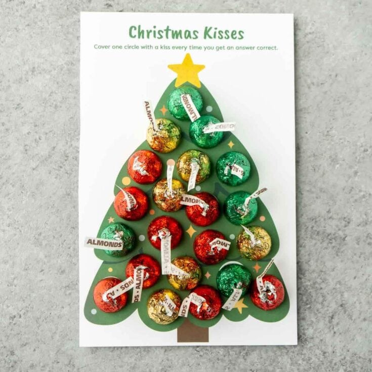 Colorful Christmas kisses game with wrapped chocolates and answer tags on a festive tree background, perfect for holiday family activities and seasonal celebrations.
