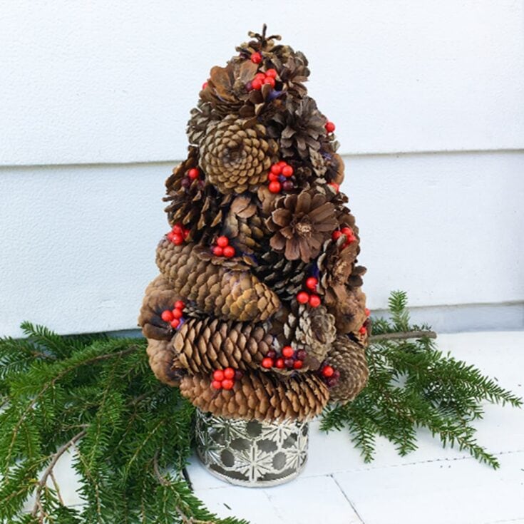 Pine cone Christmas tree with red berries in silver holder, holiday home decor centerpiece, rustic seasonal decoration, natural pinecone ornament for Christmas, festive interior styling.