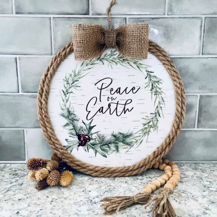 Peace on Earth holiday sign with rustic rope border, burlap bow, and greenery decor, perfect for Christmas or seasonal home decor.