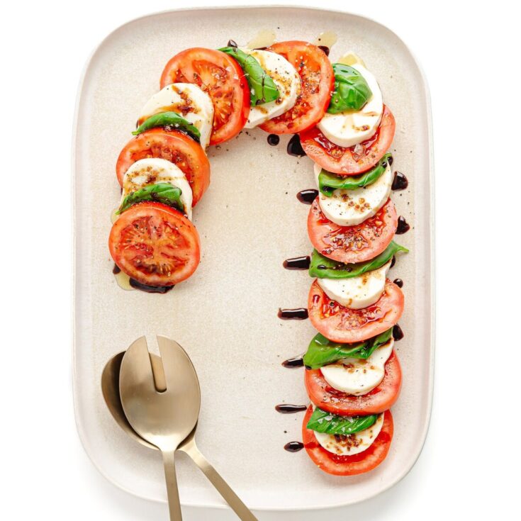 Fresh Caprese Salad Platter with Tomato, Mozzarella, Basil, and Balsamic Reduction on White Serving Plate for Elegant Appetizer or Light Meal.