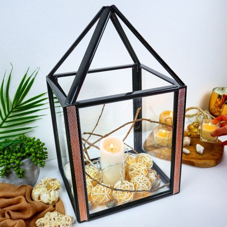 Elegant glass terrarium lantern with candles and decorative accents for home decor and romantic ambiance.