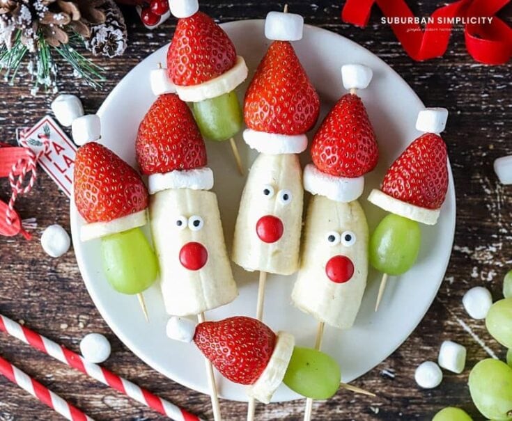 Strawberry and banana reindeer snacks with festive accents, perfect for holiday parties and kid-friendly Christmas treats, featuring adorable edible faces on skewers.