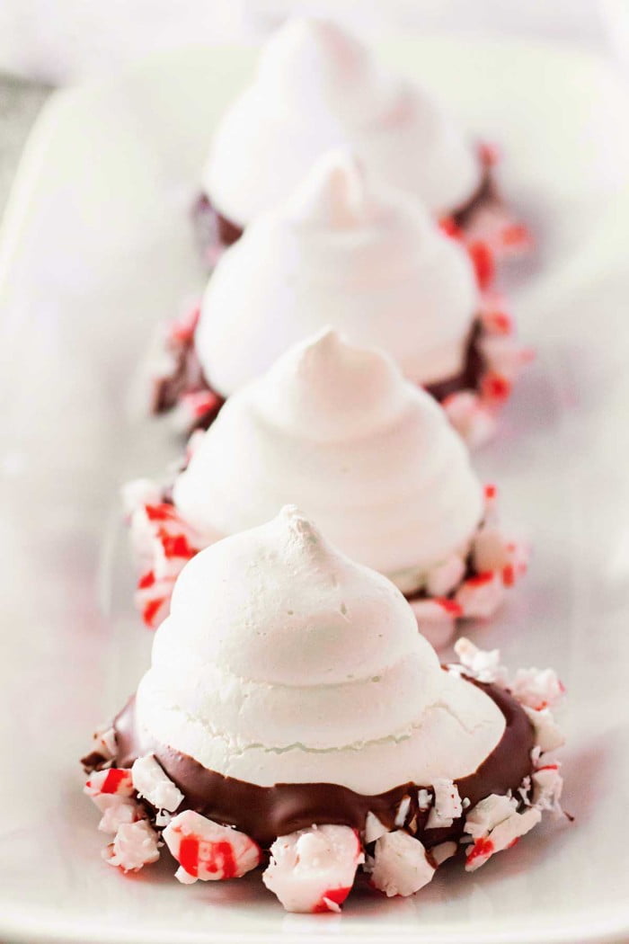 Marshmallow Christmas treats with chocolate and crushed peppermint on a white plate for holiday desserts and festive snacks.